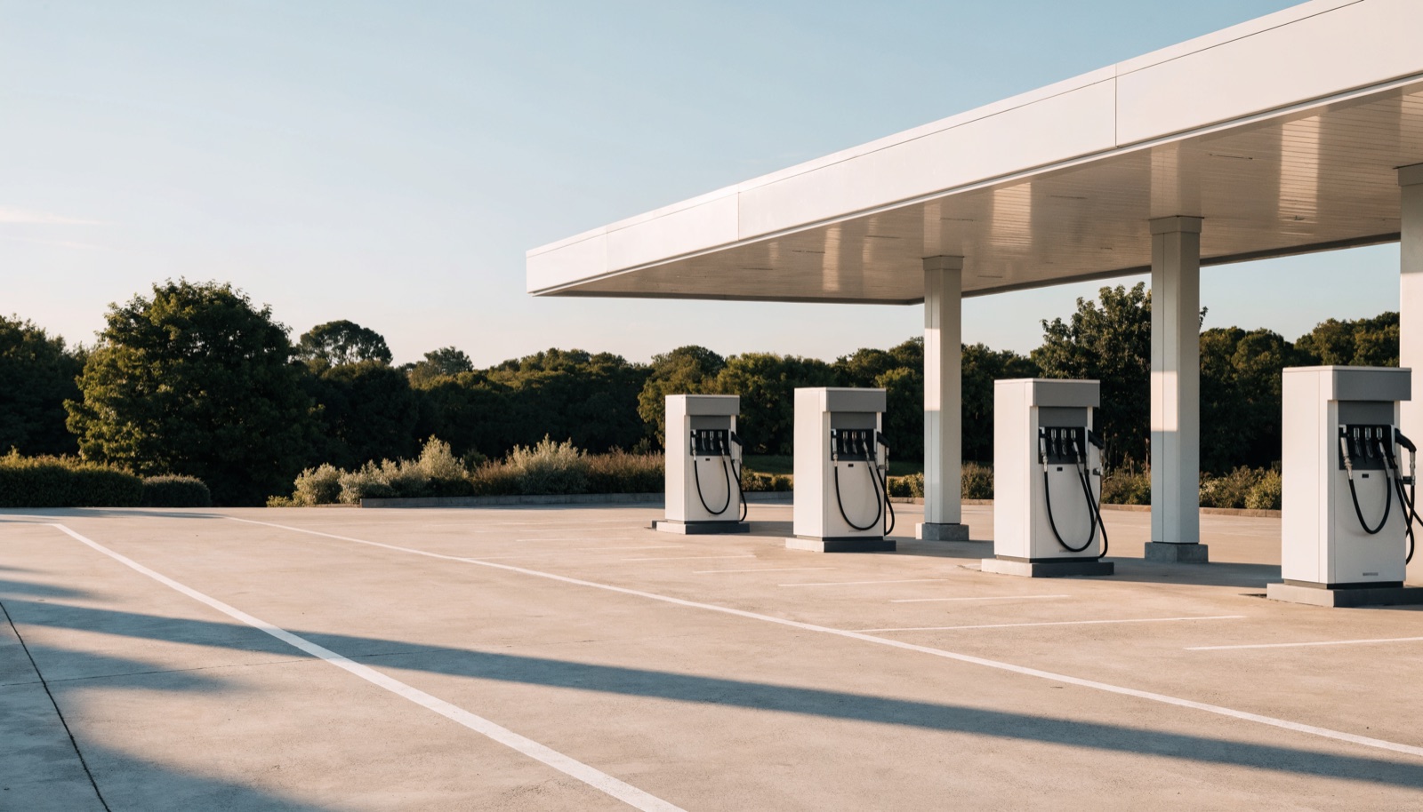 The clean concrete lot of a gas station under a plain white canopy.